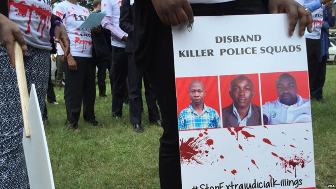 FILE - A protester holds a sign picturing human rights attorney Willie Kimani, his client. Josephat Mwenda. and their taxi driver. Joseph Muiruri. allegedly killed by police, at a rally in Nairobi, Kenya, July 4, 2016. (J. Craig/VOA)
